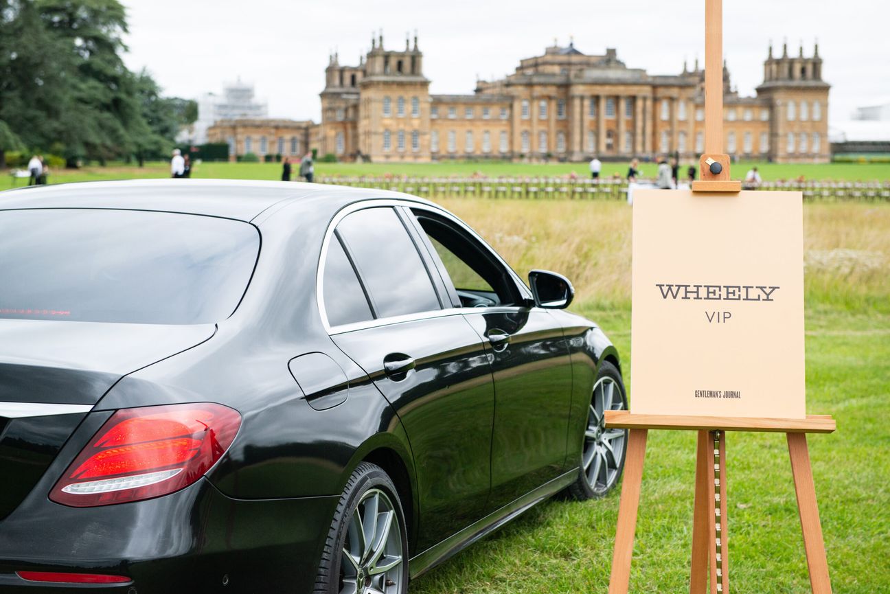 Car parked on a field next to a sign saying "Wheely VIP" in front of Blenheim Palace
