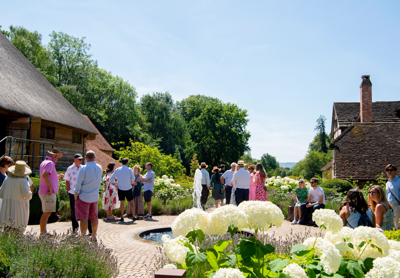 Gravetye Manor garden and fountain surrounded by people on a sunny day