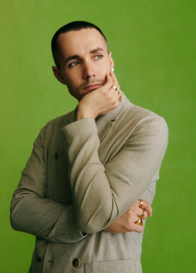 Jonah Hauer-King in a grey blazer in front of a green studio screen