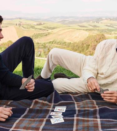 Pierce Brosnan and his son Paris Brosnan playing cards on a picnic blanket wearing Paul&Shark’s jumpers