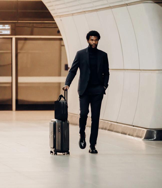 man walking through London underground with suitcase and bag