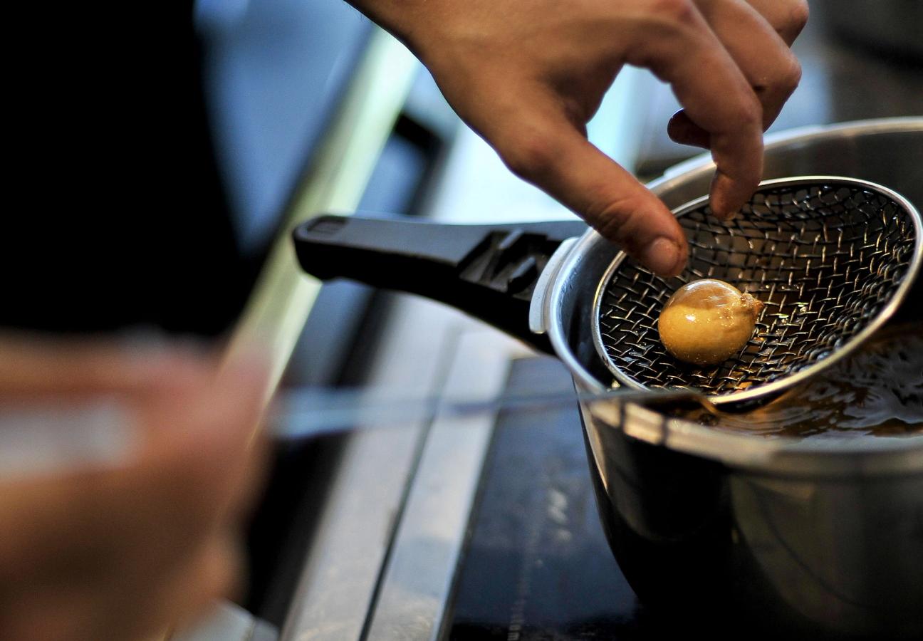 A spherified food item, being lifted out of a bath in the El Bulli kitchen