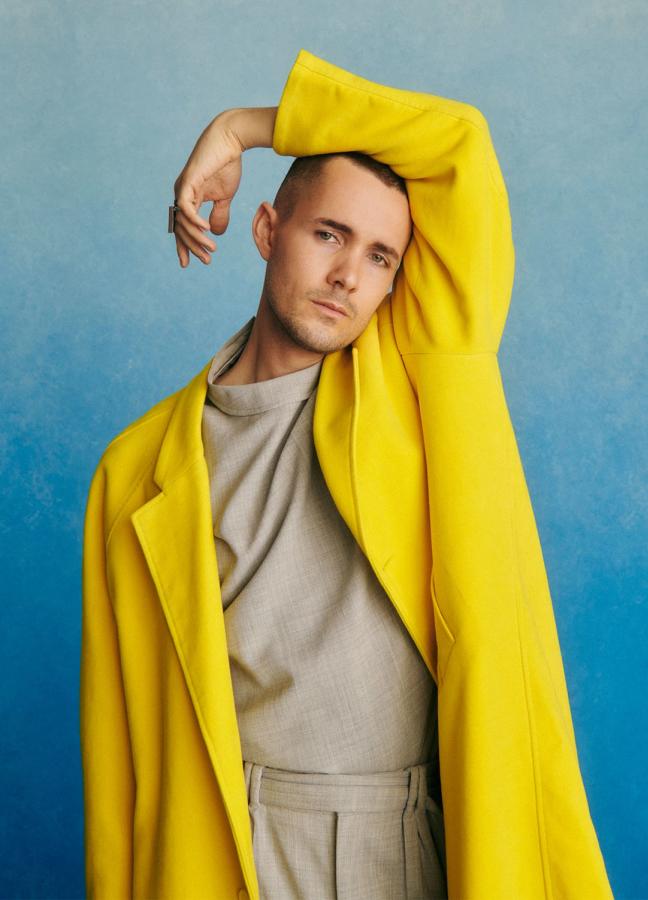 Jonah Hauer-King wearing a yellow jacket in front of a blue studio background