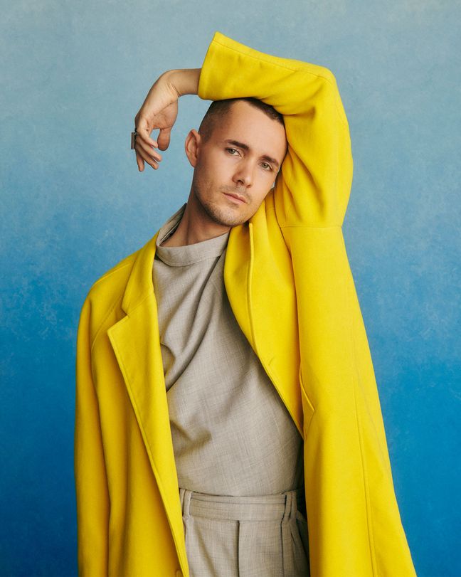 Jonah Hauer-King wearing a yellow jacket in front of a blue studio background