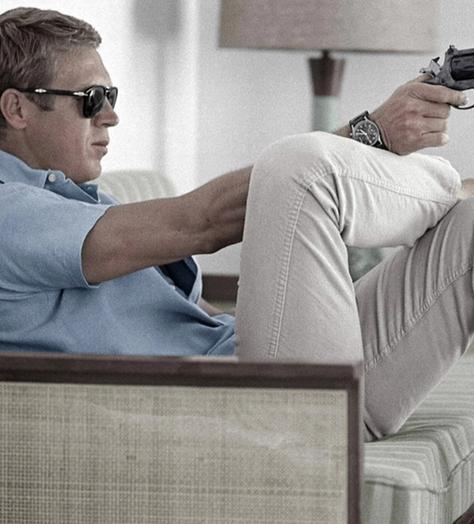 steve mcqueen wearing polo shirt and trainers pointing a gun