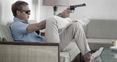 steve mcqueen wearing polo shirt and trainers pointing a gun