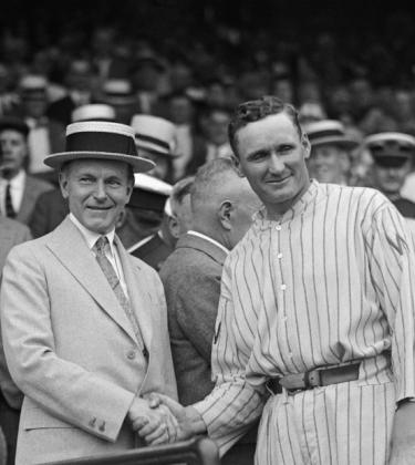 US President Calvin Coolidge and Washington Senators pitcher Walter Johnson shake hands, presenting the "American League diploma" for the Senators winning the AL in 1924.