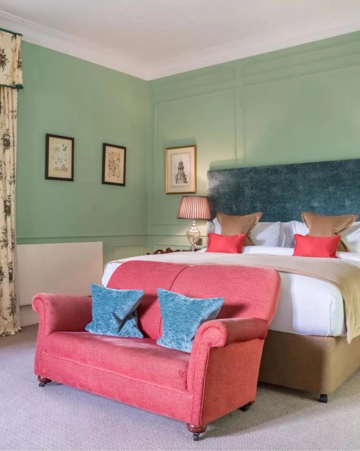 Bedroom with green walls and pink seating at Stapleford Park