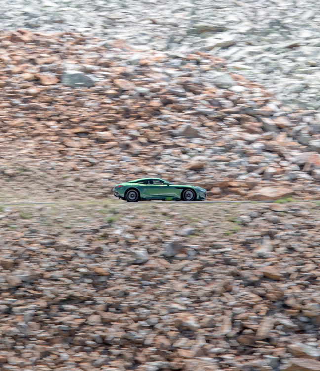 Green Aston Martin DB12 driving on a rocky landscape