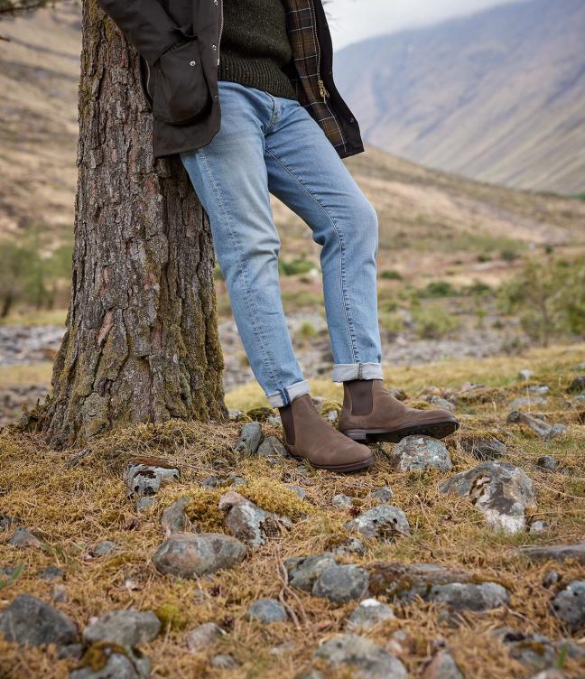 Man wearing Crockett & Jones Chelsea 5 shoes in Natural Rough-Out Suede around the Trossachs leaning against a tree