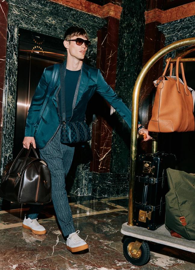 Model Kit Butler walking through a hotel lobby with a trolley of suitcases and bags