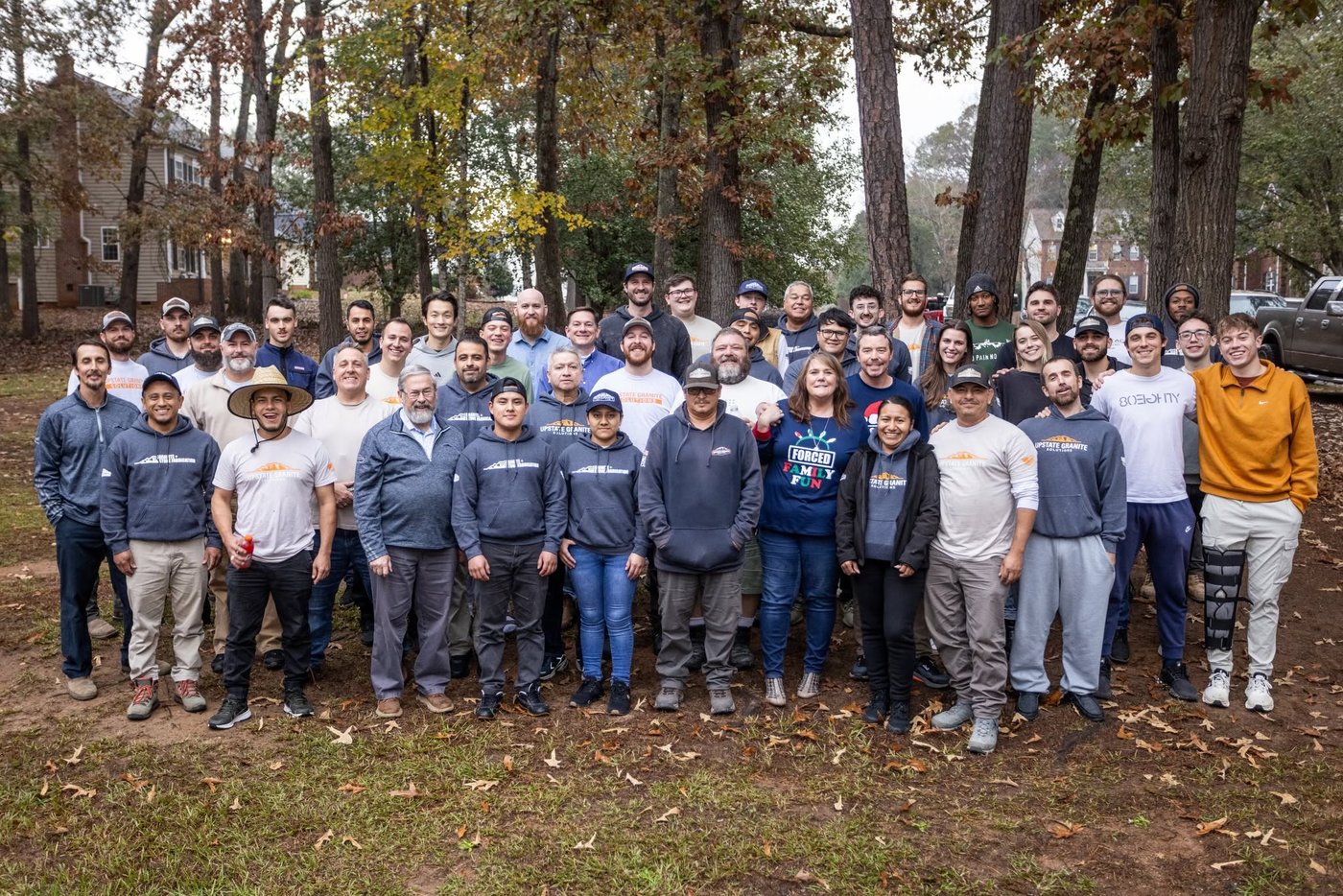 The Upstate Granite team gathered together outdoors among pine trees.