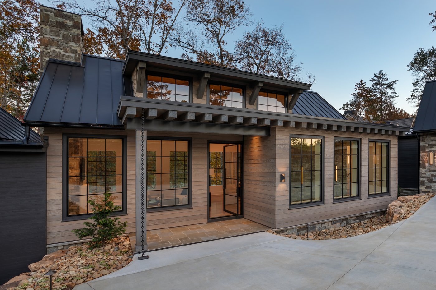 A home exterior clad in wood siding with a standing-seam metal roof and black-framed windows.