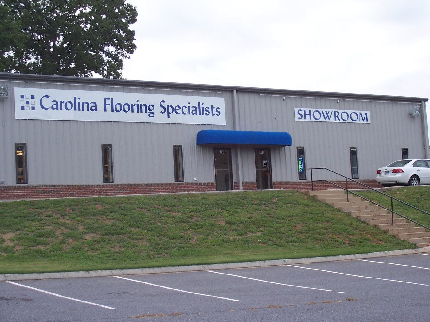 The Carolina Flooring Specialties showroom building with a blue awning over the entrance.