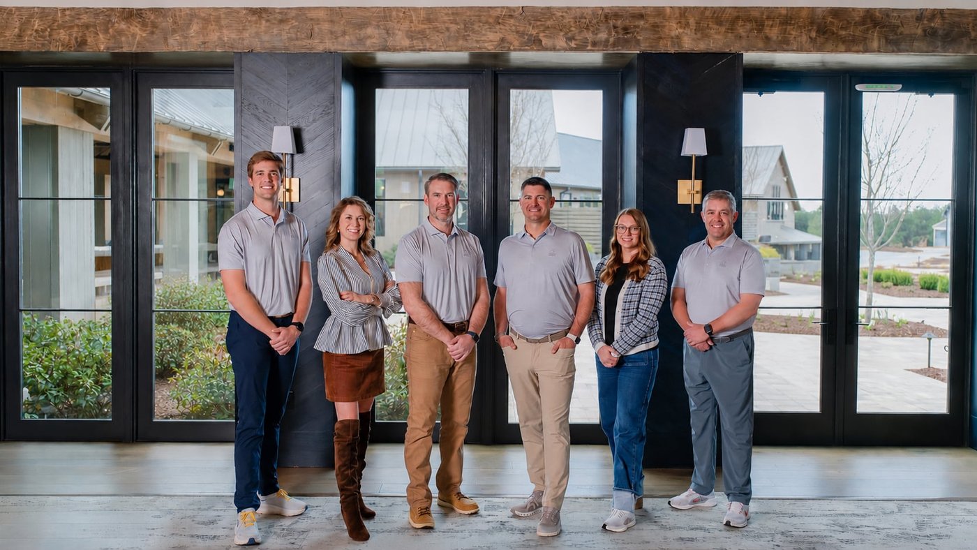 The Haven Valley Homes team standing in front of tall black-framed windows.