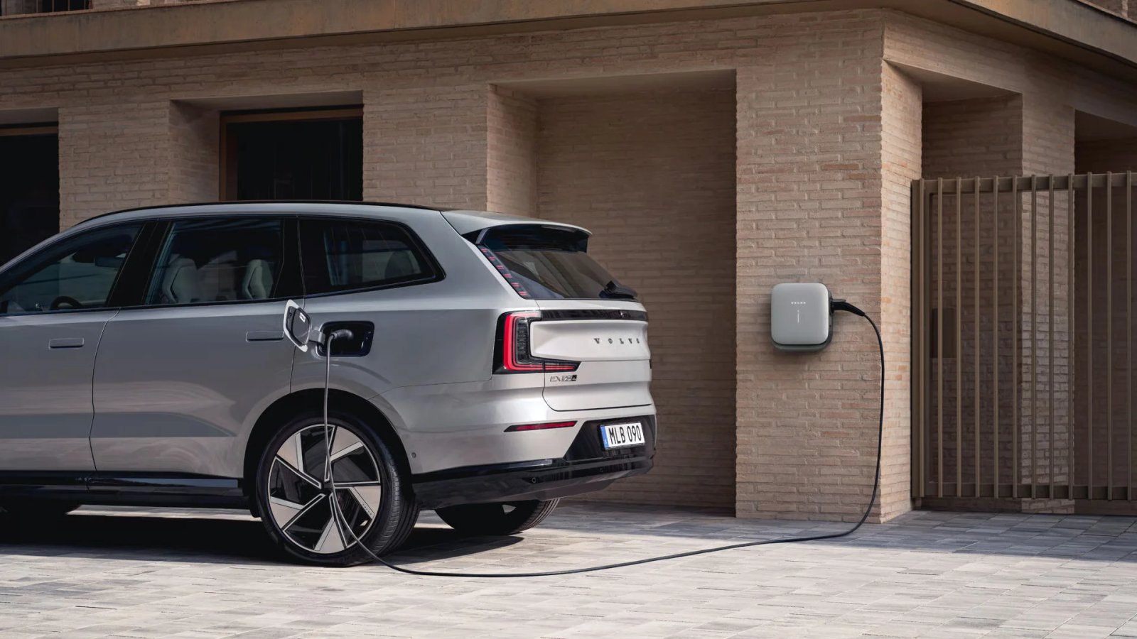Volvo-sähköauto latautuu tiiliseinään asennetusta Volvo-latausasemasta