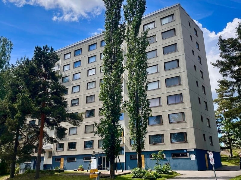 The eight-storey block of flats of Asunto Oy Kotikonnuntie 2, with pine trees and two tall poplars in front