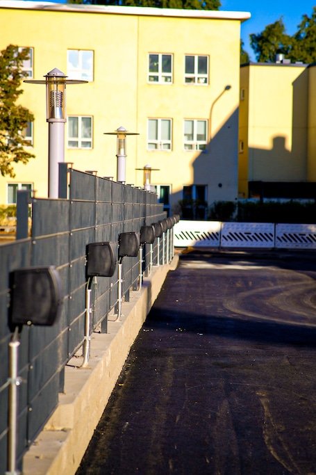Rivi autopaikkojen lämmitystolppia kerrostalon pysäköintialueella.