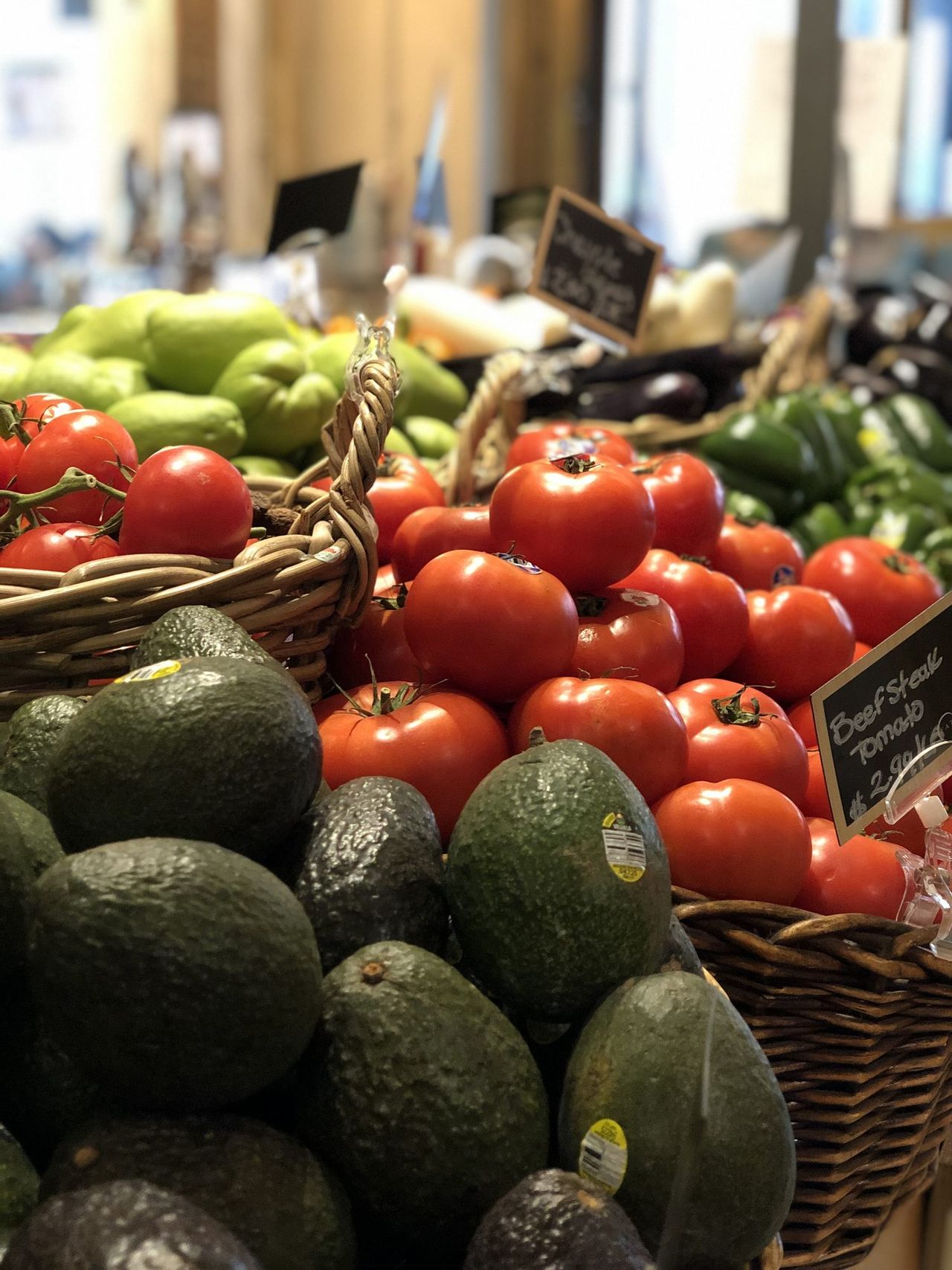 Baskets of tomatoes and avocados at a produce market