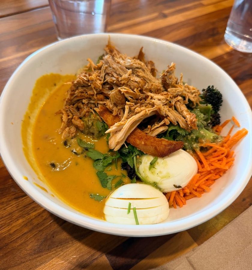 A warm bowl of soup topped with vegetables