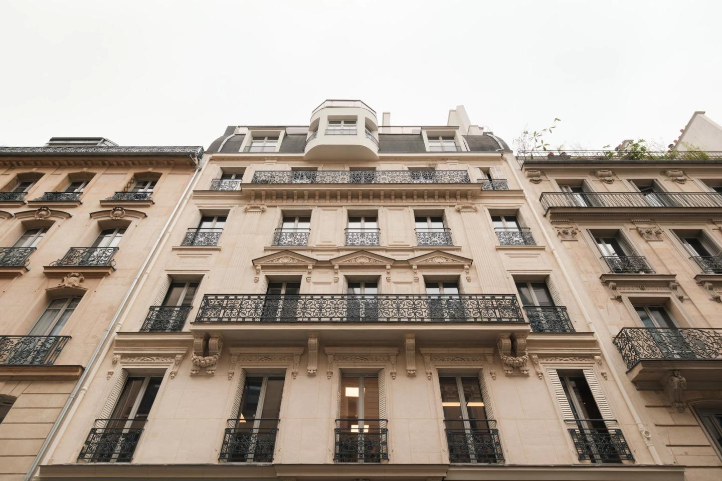 Photo of the Haussmann-era facade at 25 rue Drouot, continuous wrought-iron balconies and dormers, Paris 9th