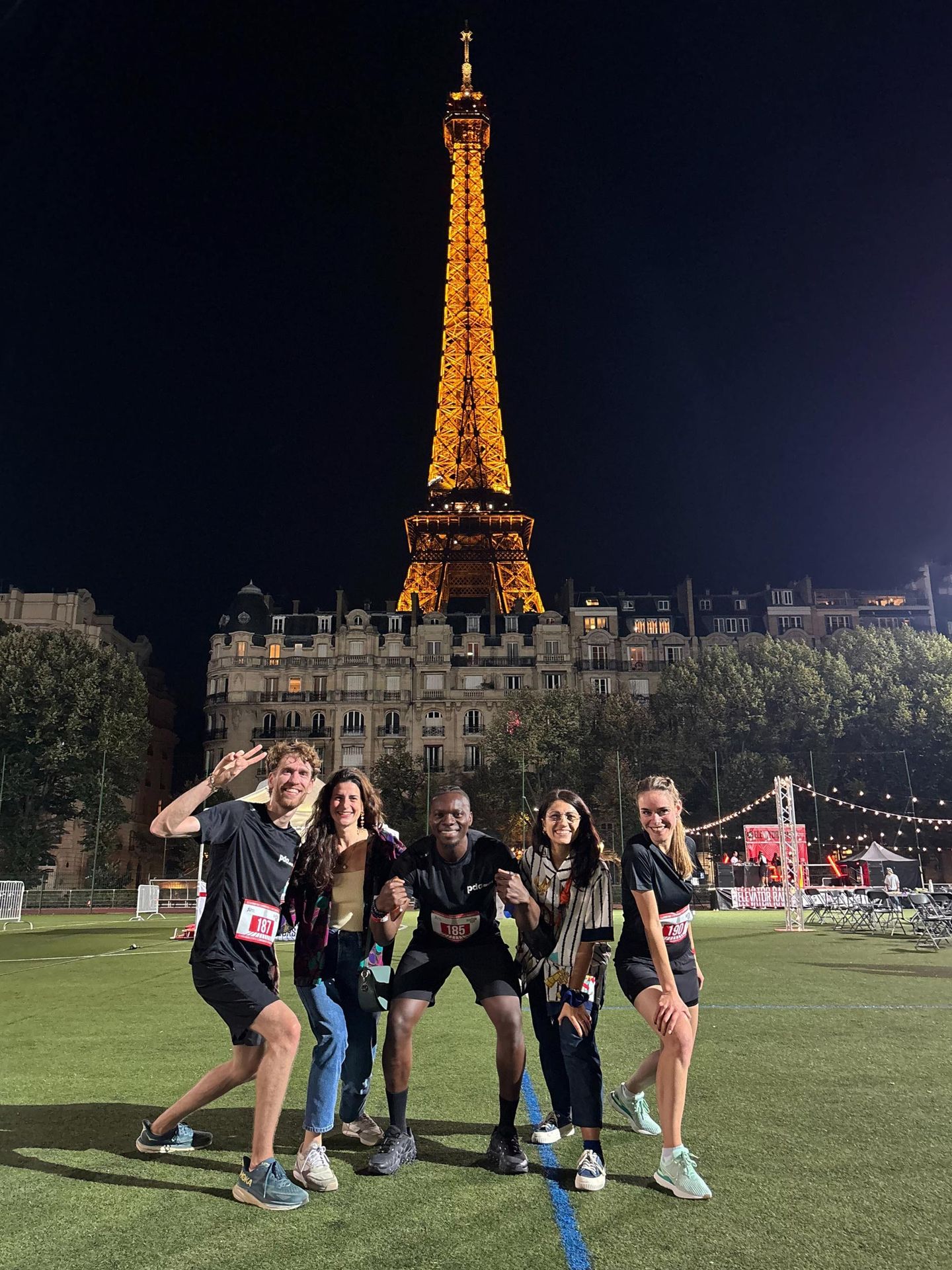 Photo de nuit de l'équipe PDA Architecture devant la tour Eiffel illuminée lors de l'Elevator Race 2025, Paris
