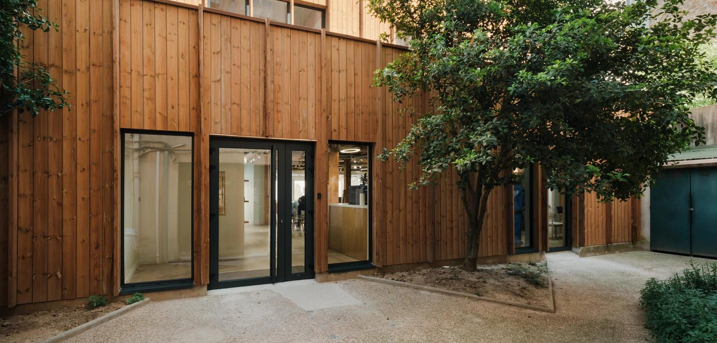 Photo de la façade en bardage bois du tiers-lieu du 20 rue Clavel sur sa cour arborée, Paris 19