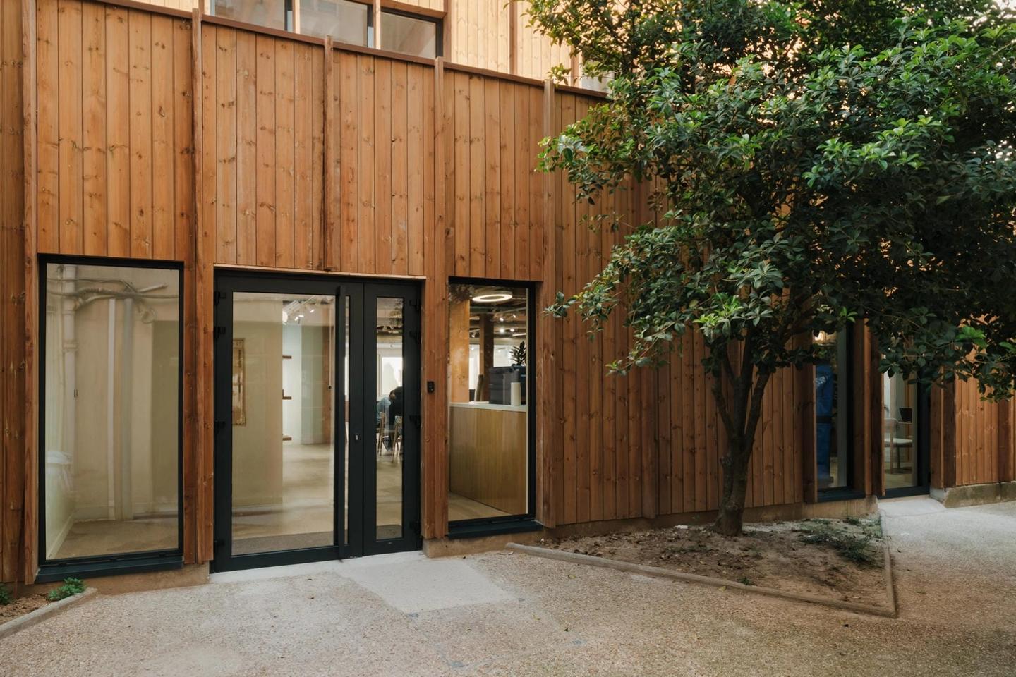 Photo of the timber-clad facade of the 20 rue Clavel third place on its tree-lined courtyard, Paris 19th