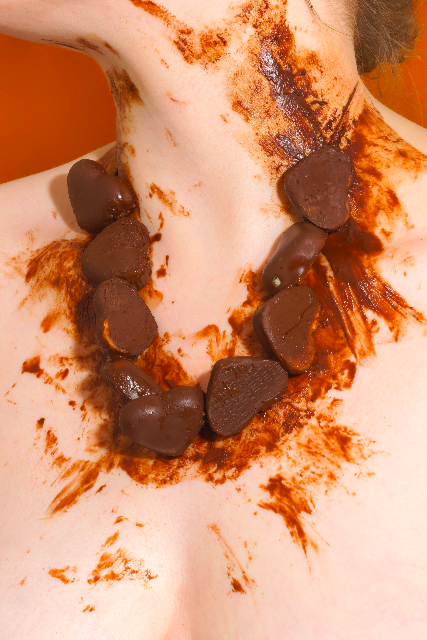 A close-up photograph of a bare neck, wearing a chain of melted chocolates.
