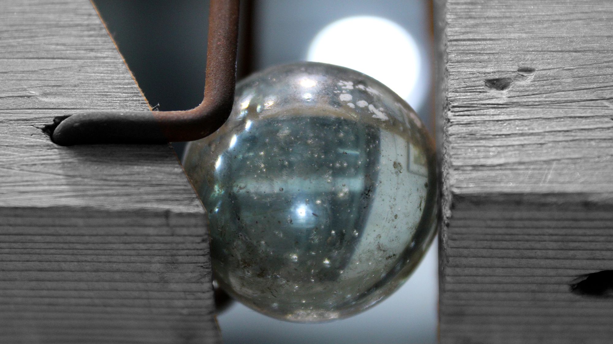 Close up image of a glass sphere wedged between two pieces of wood 