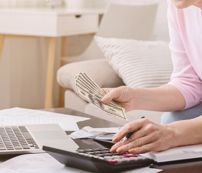 Woman setting aside money for bills while using the calculator.