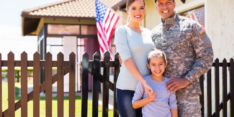 Family of military standing in front of new house.