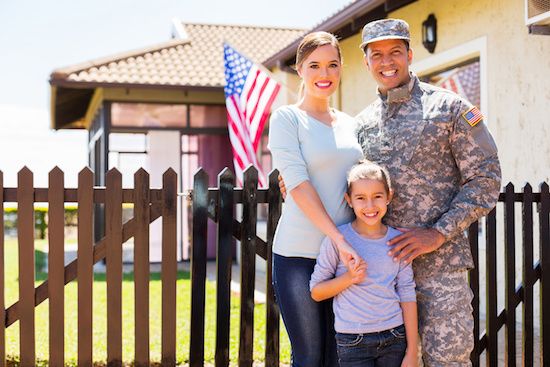 Family of military standing in front of new house.