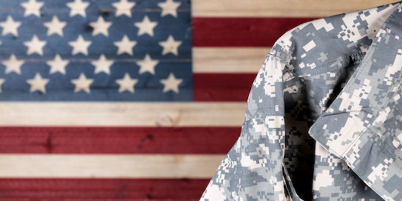 Military standing in front of American flag.