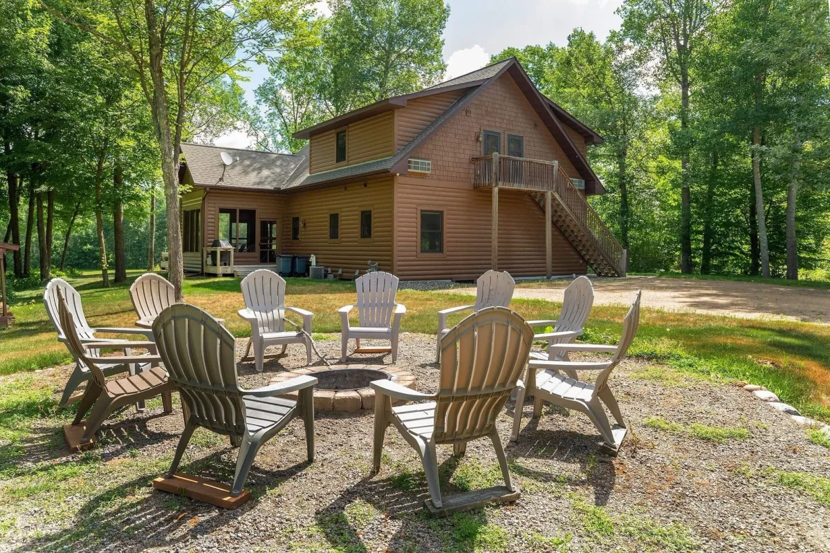 Adirondack chairs circling the outdoor fire pit behind The Cottage at Golden Eagle