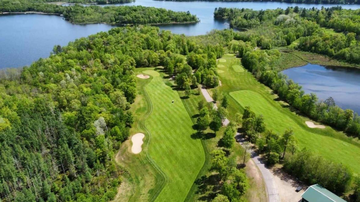 Aerial view of Golden Eagle’s fairways winding through Northwoods forest along Eagle Lake