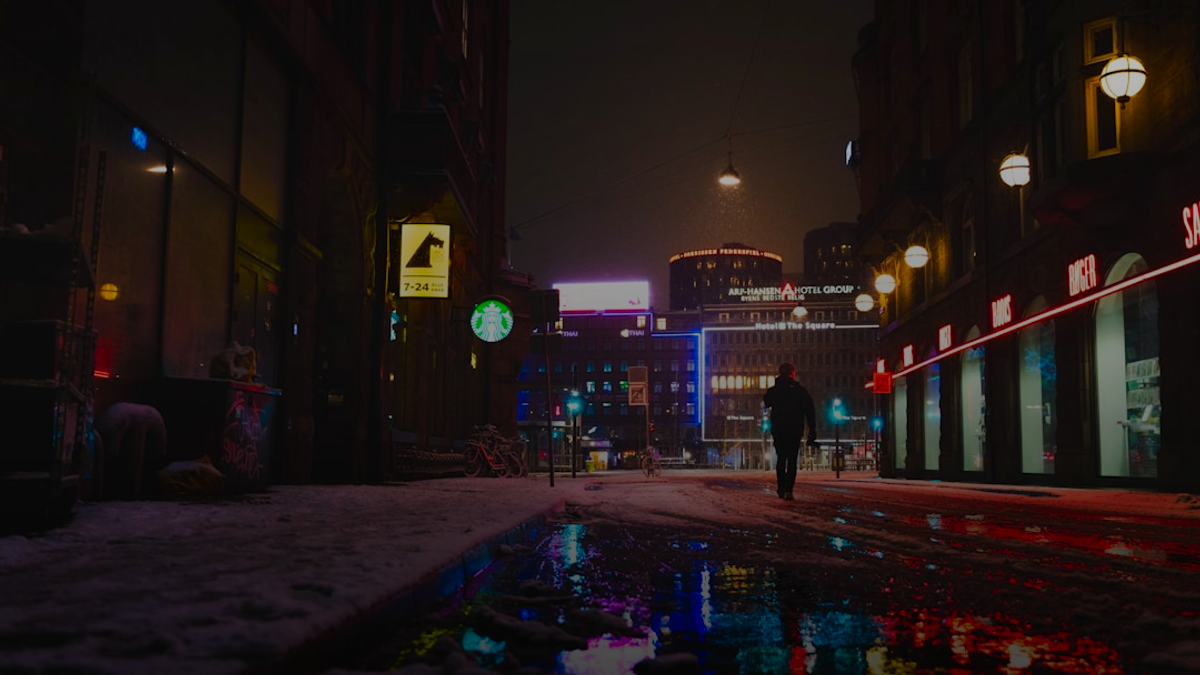 man in black jacket walking on street during night time