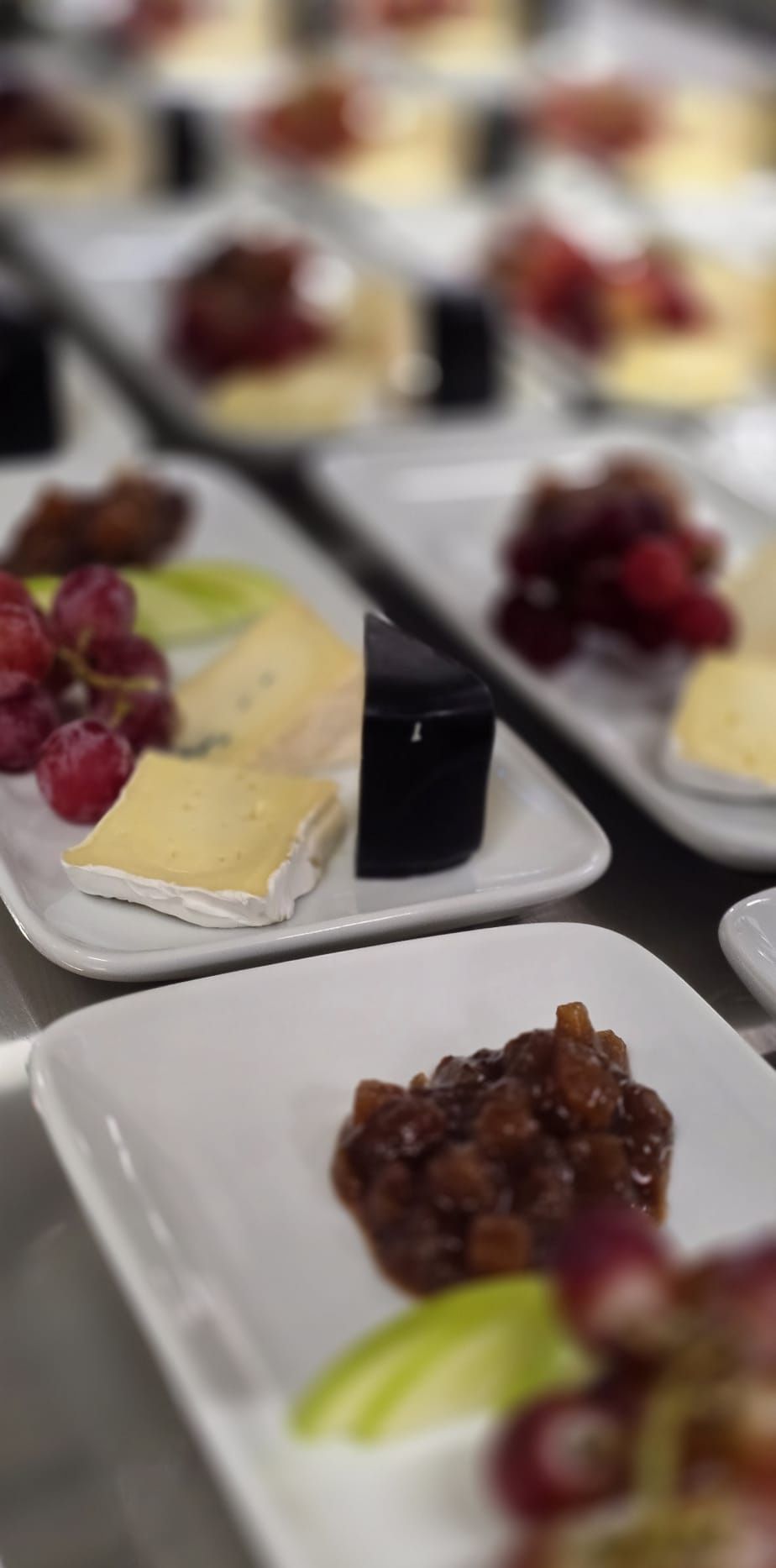 Cheese boards plated with grapes and chutney, ready to go out