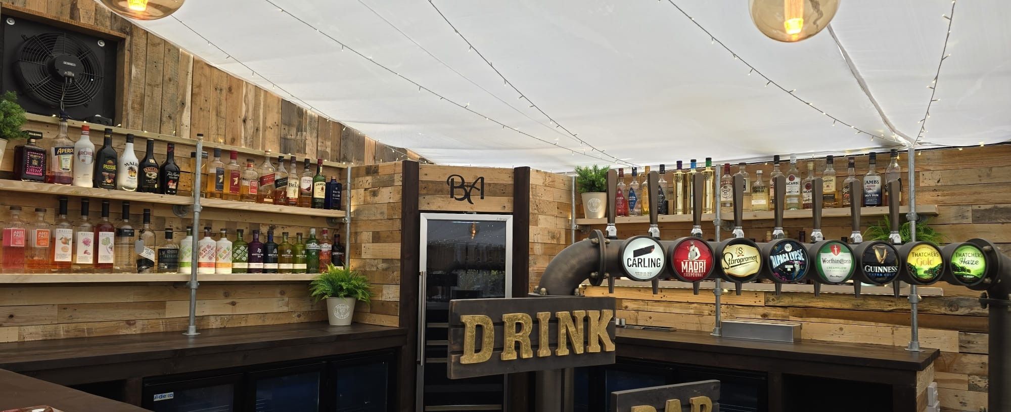The timber conservatory bar under canvas, with its eight tap line up and back bar shelves