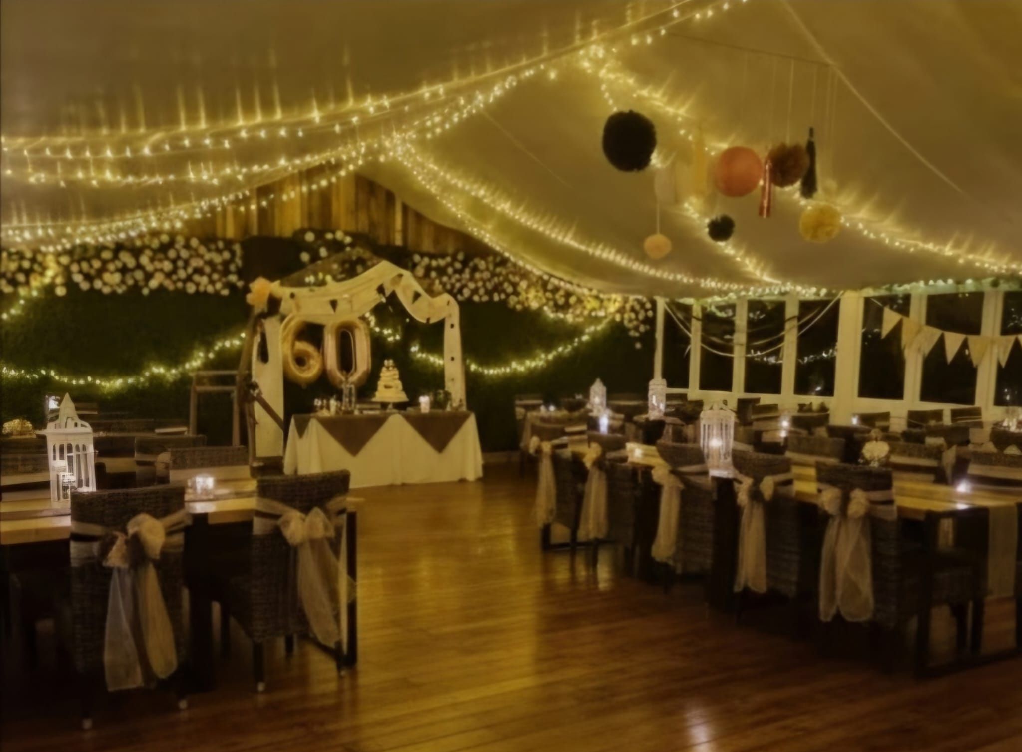 A party room under a canopy of fairy lights, with hessian sashes and a decorated backdrop