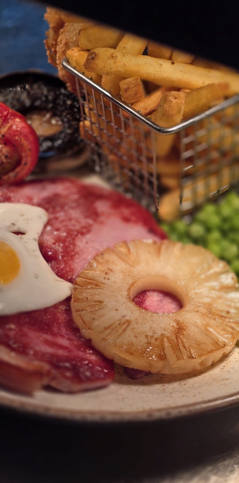 Gammon steak with a fried egg, grilled pineapple, peas and a basket of chips