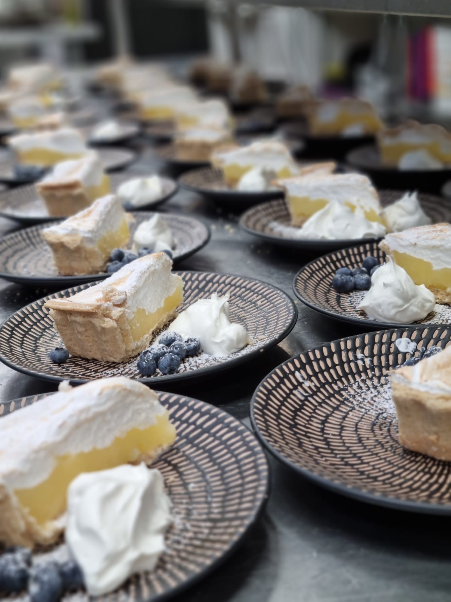 Slices of lemon meringue pie with cream and blueberries on patterned plates