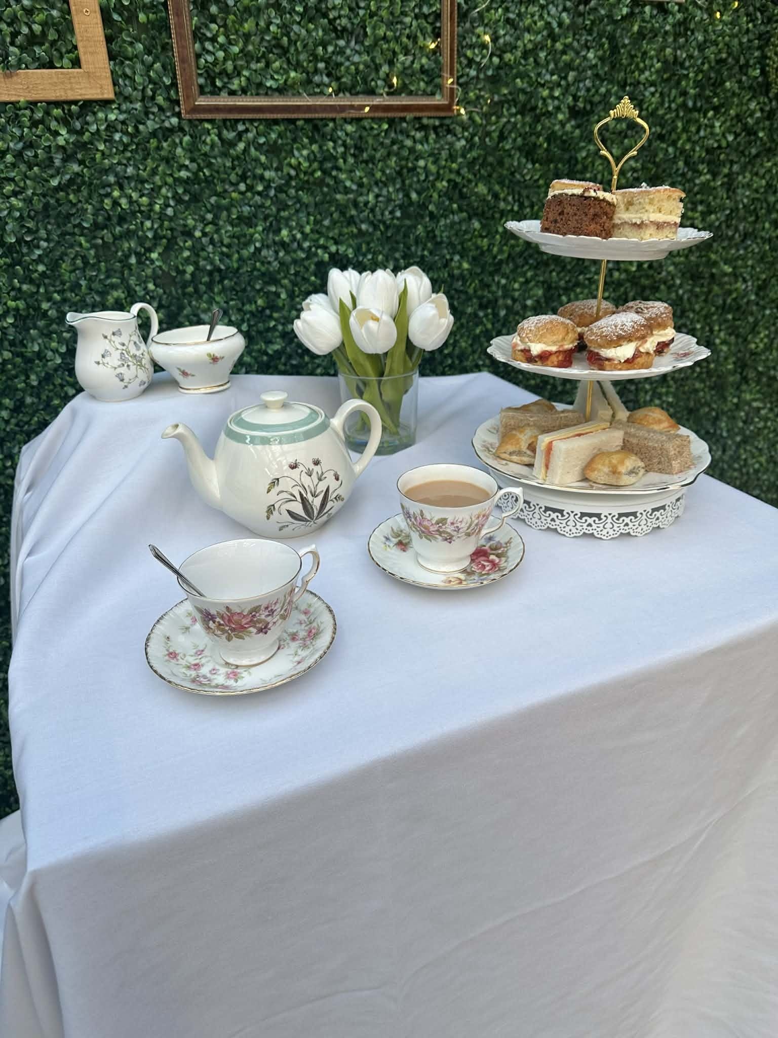 Afternoon tea on vintage china: a three tier stand, teapot and white tulips