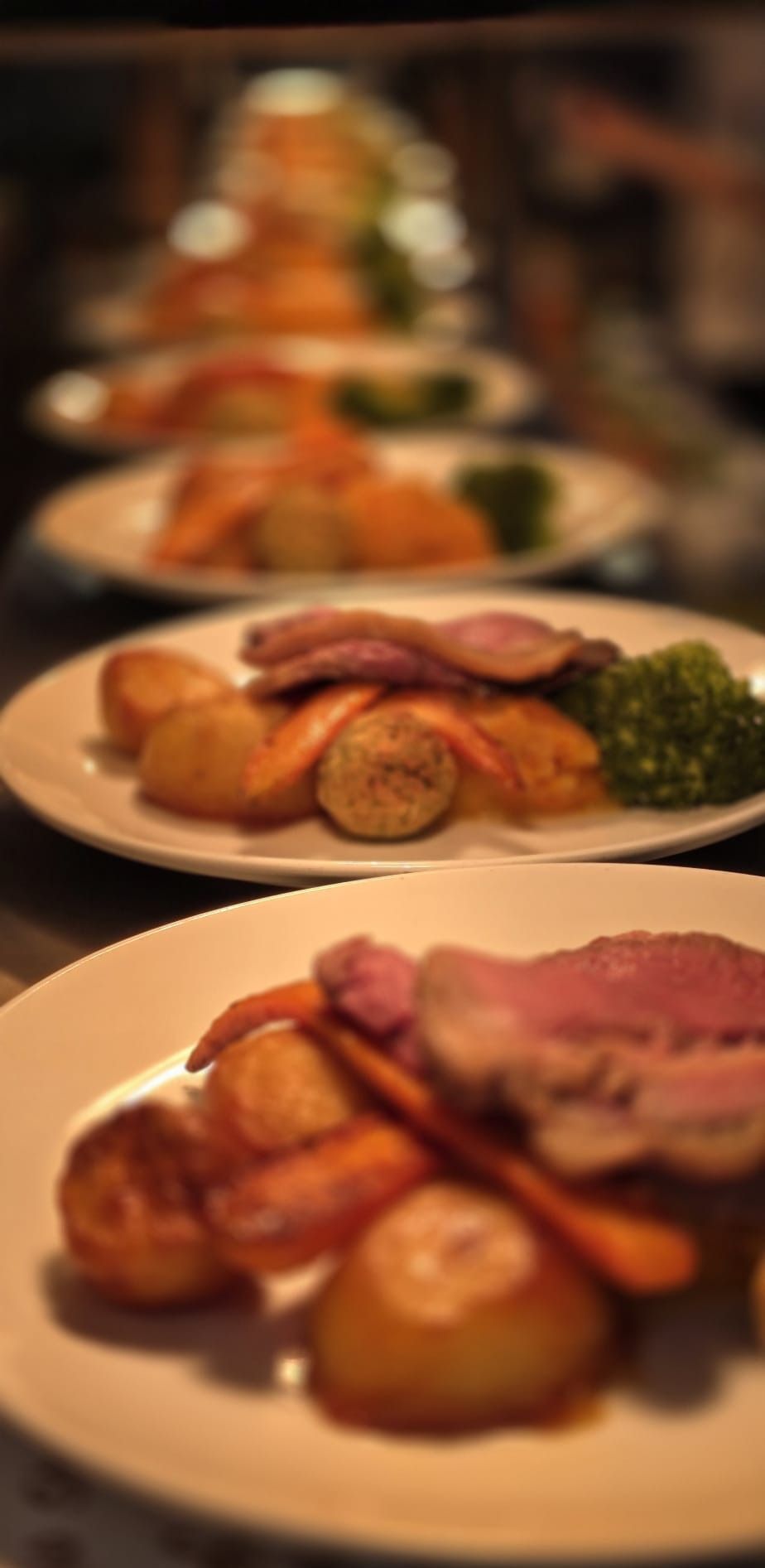 Plates of roast beef with roast potatoes, carrots and greens