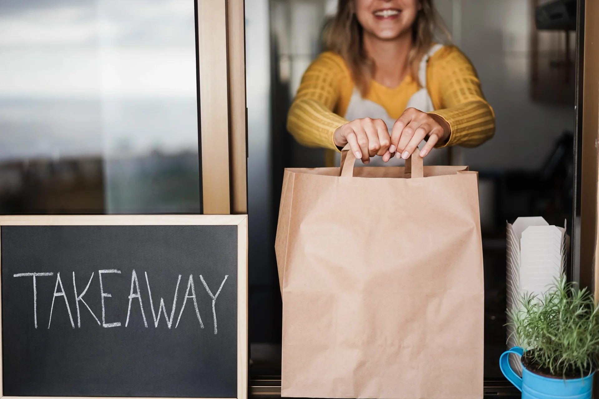 Woman holding food bag in front of chalkboard for tech trends.