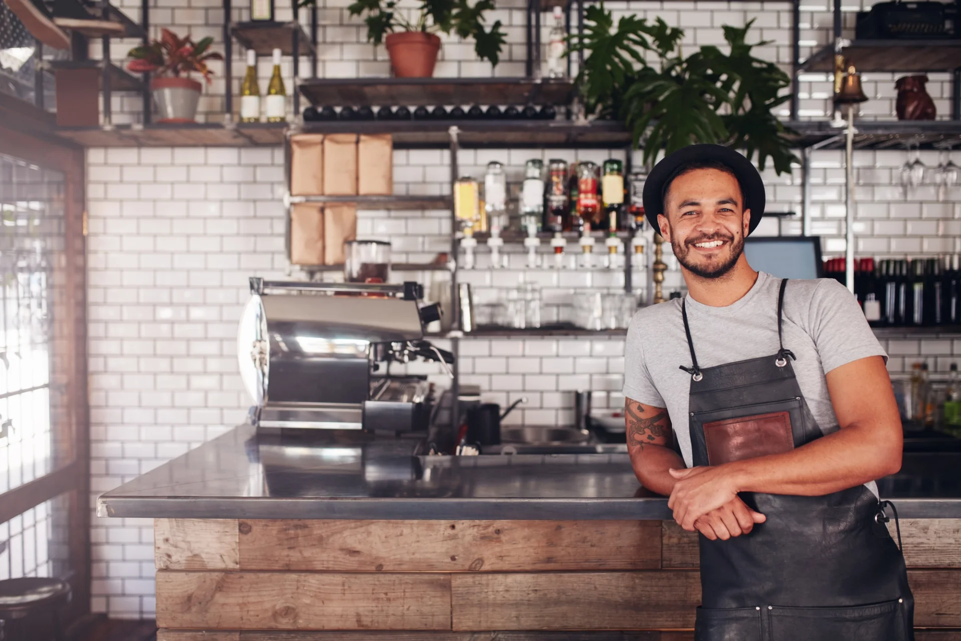 A man standing in front of a bar counter at a coffee shop, displaying a friendly smile.