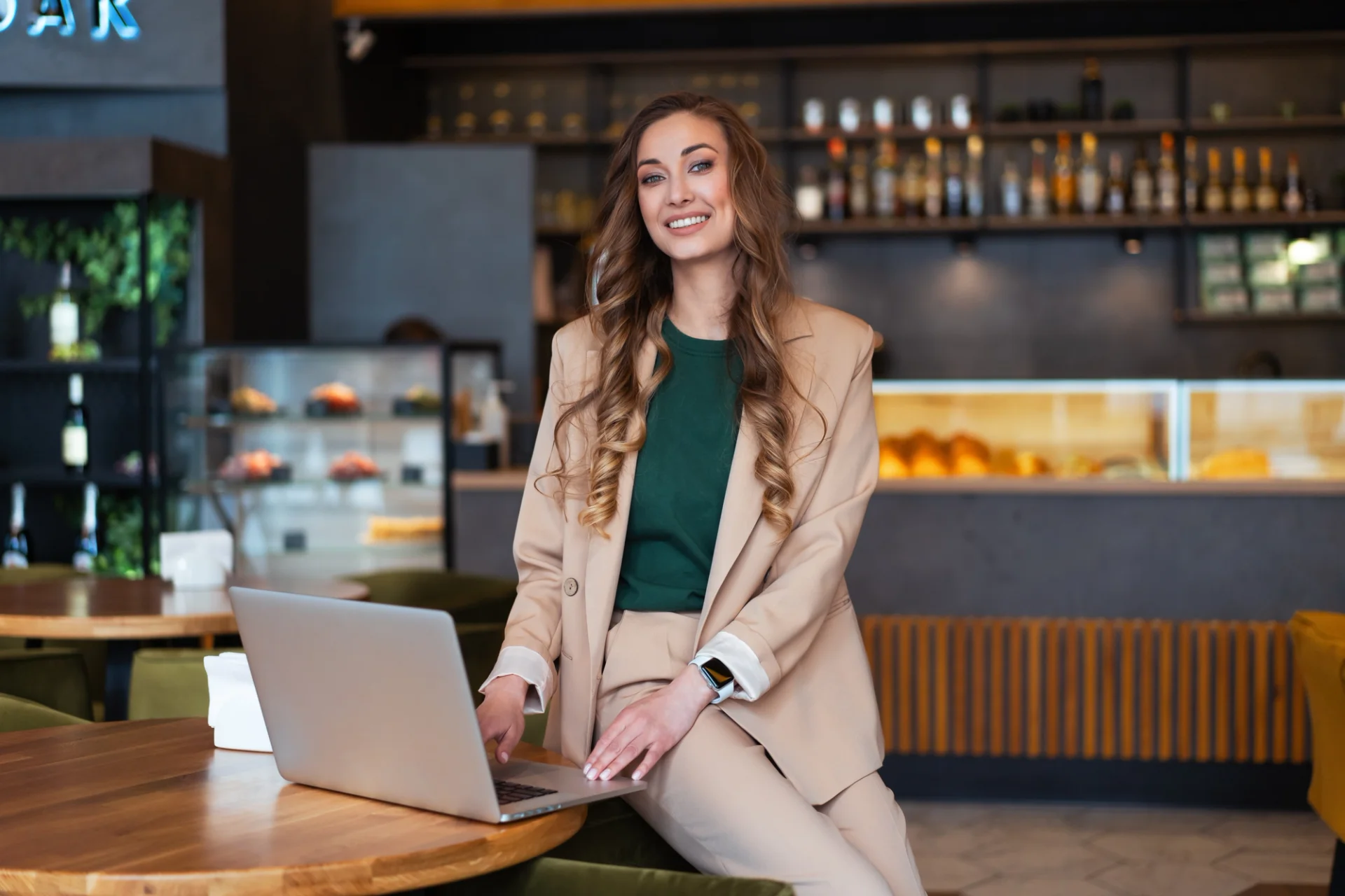 A skilled and dedicated Restaurant Manager multitasking on her laptop at a table, ensuring smooth operations in a restaurant environment.