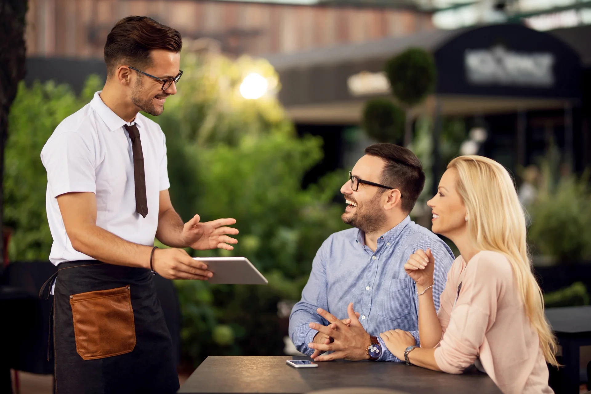 Restaurant waiter assisting customers with tableside payment.