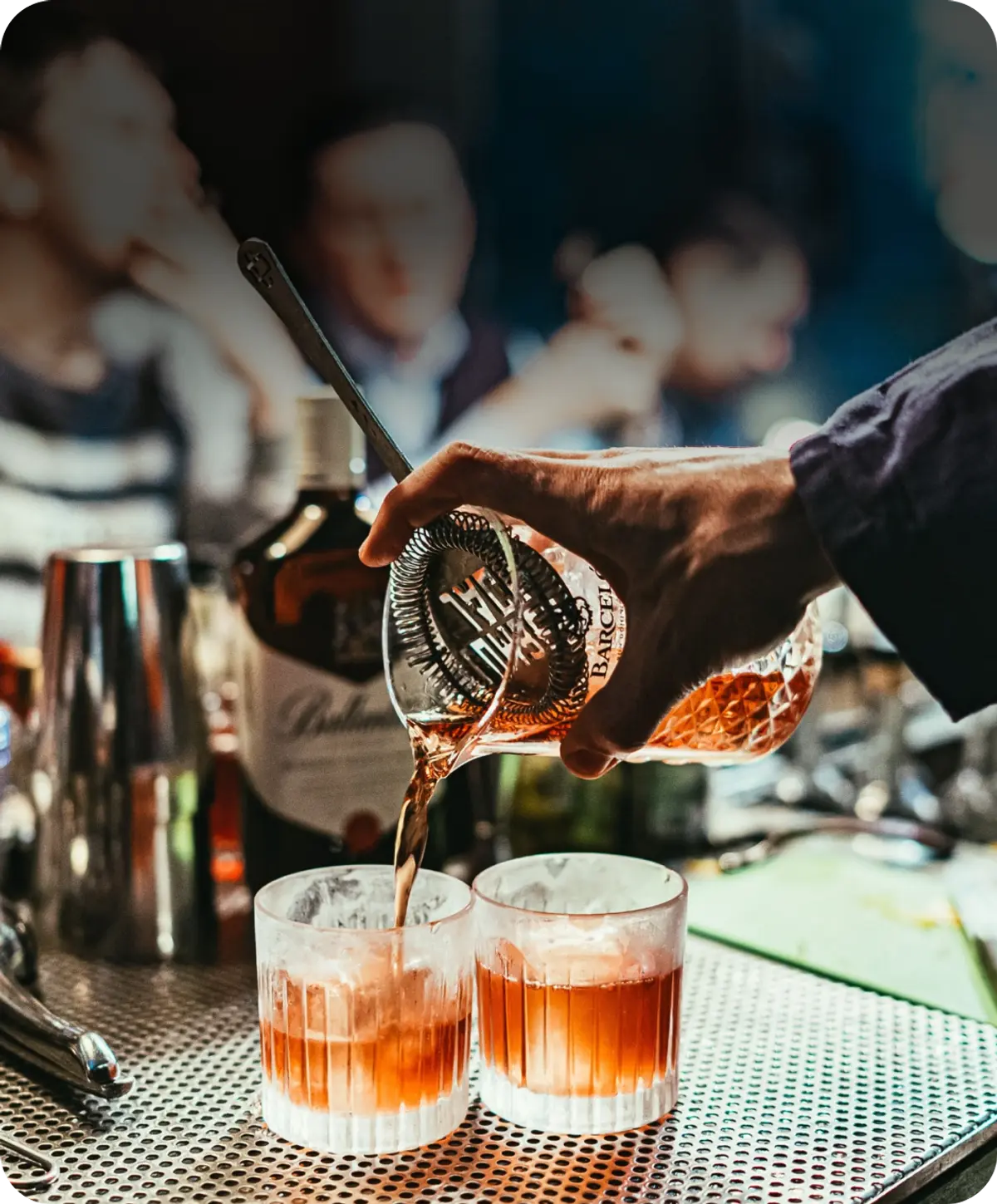 A bartender expertly pours a drink into two glasses, creating a delightful concoction for patrons to enjoy.