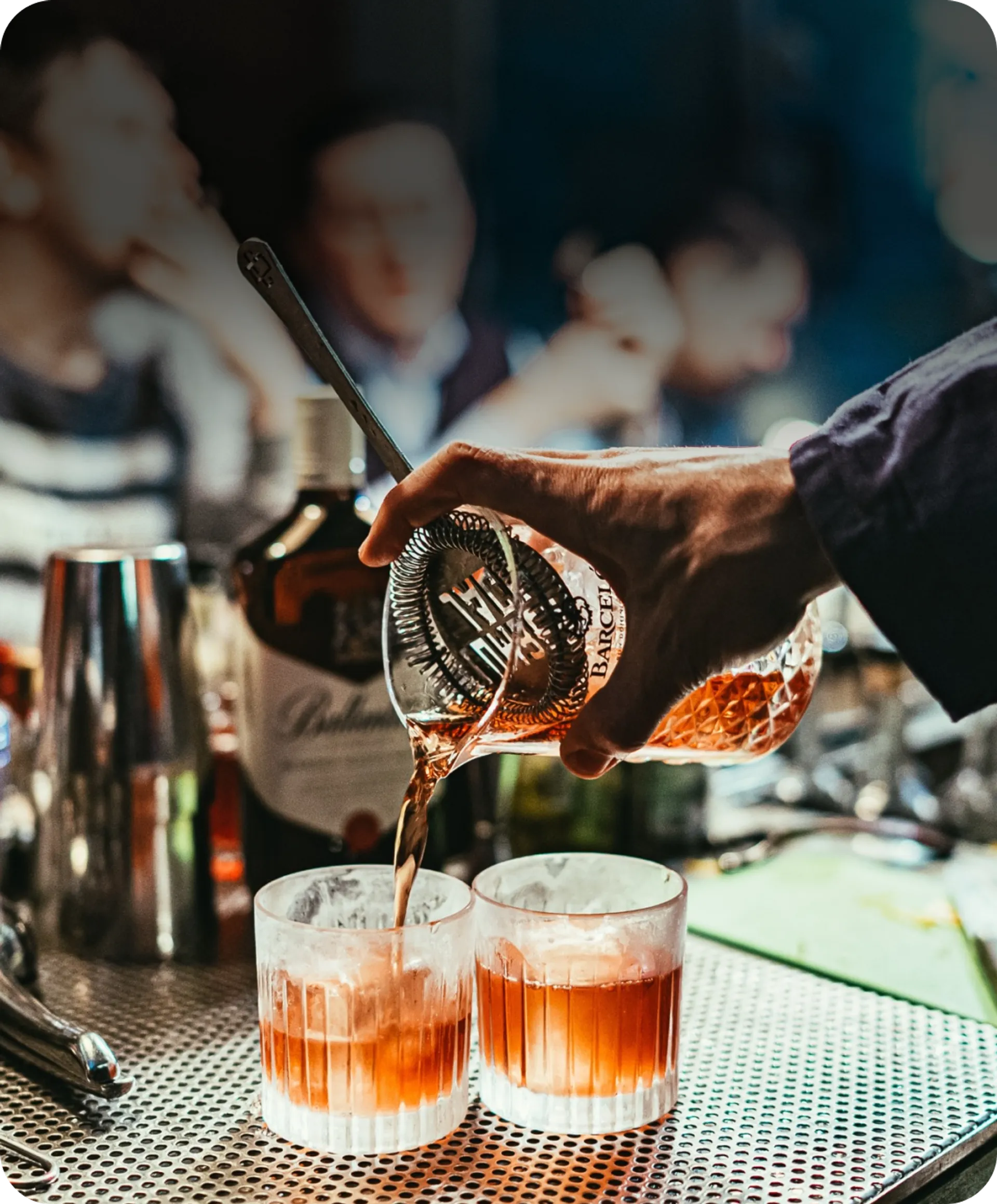 A bartender expertly pours a drink into two glasses, creating a delightful concoction for patrons to enjoy.